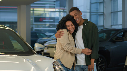 African American couple buyers customers happy owners joyful smiling woman man cuddling choosing modern car at vehicle salon showroom rent buy automobile buying luxury auto dealership rental service