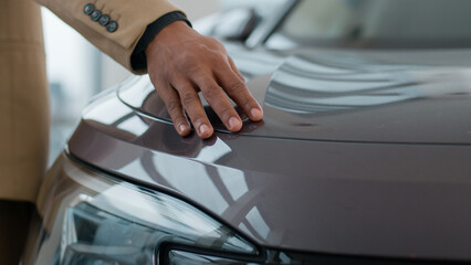 Male hand on new electric lead car headlight future of auto industry eco modern crossover automobile sale at dealership showroom. Unrecognizable african american business man buyer stroking vehicle