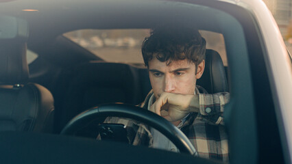 Displeased upset sad Caucasian man guy male driver car owner inside automobile on parking lot using...