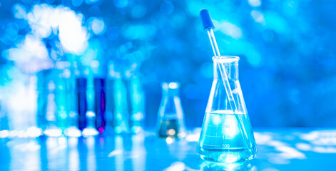 Chemistry science nature concept. A blue beaker with a blue liquid in it sits on a table next to several other beakers