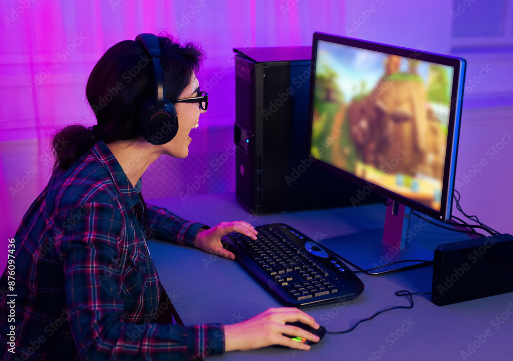 Poster this image shows a young woman wearing a plaid shirt and headphones, playing a video game on a compu