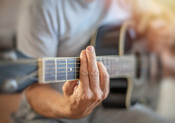 A man plays a guitar, shot in close-up.