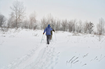Snow-covered field in a countryside and ski tracks left by unidentified skiers