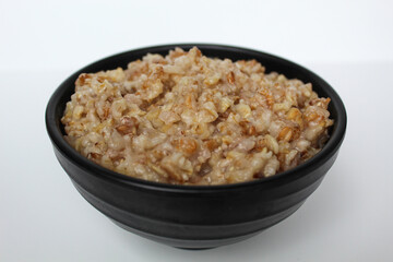 Cooked plain rolled oat inside black bowl, Isolated on white background