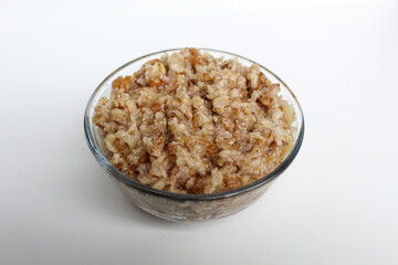 Cooked plain rolled oat inside transparent bowl, isolated on white background