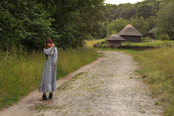 Young brunette woman in vintage dress walking in a countryside by the brick road