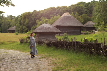 Young brunette woman in vintage dress walking in a countryside by the brick road