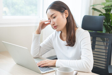 Tired asian young woman burnout, stressed from problem work at desk in office, looking at laptop...