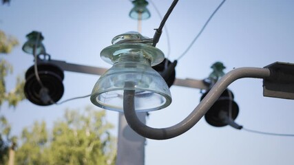An electrical insulator is connected to power lines against a backdrop of a clear sky and other insulators. The image underscores the significance of reliable electrical infrastructure.