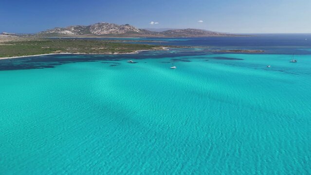 Great turquoise water on La Pelosa beach, Sardinia island, Italy. Aerial shot of white yachts in blue sea water