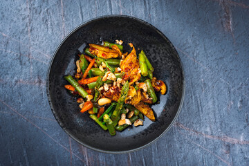 Traditionelle würzige Hähnchenfilet Nuggets mit grünem Spargel Cashewnüssen und Brokkoli in süß-saurer Soße serviert als Draufsicht in einer Design Schale mit Textfeld