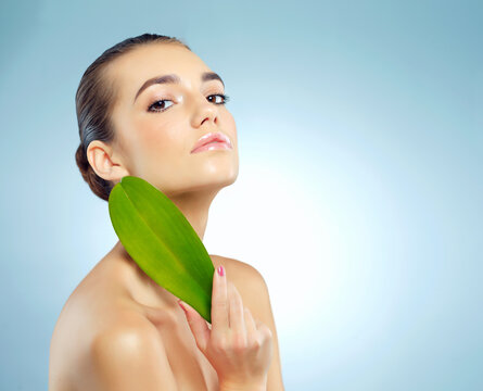 Girl, portrait and leaf in studio for skincare or natural dermatology, organic treatment and ingredient for cosmetics. Woman, blue background and leave for sensitive skin, anti aging and mock up.