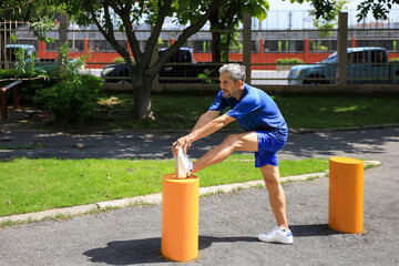 Senior Asian man is stretching his leg muscle during warm up exercise work out in the morning at public park for healthy and longevity