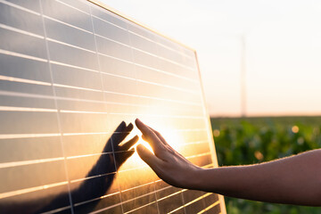 Close-up of a hand touching a solar panel at sunset