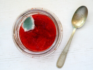 Moldy Strawberry Jam in a Glass Jar with Spoon on a Wooden Table