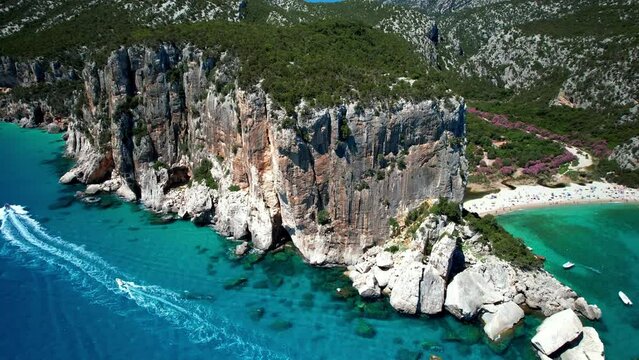 Cala Luna Beach Sardinia Aerial Drone cinematic footage  Gulf of Orosei Scenic View with Sea Caves & Majestic Cliffs White Sand and Turquoise Water with Boats, Luxury Travel Destination Italy 4K Video