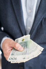 A man in a suit holding money in his hand. Polish zloty.
