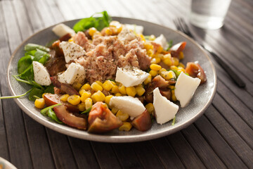 Plate of salad with tuna, corn, tomatoes and arugula