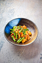 Traditionelle würzige Hähnchenfilet Nuggets mit grünem Spargel Cashewnüssen und Brokkoli in süß-saurer Soße serviert als Draufsicht in einer Design Schale mit Textfeld