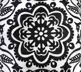 Close up of random floral pattern, flower medallion in black and white fabric finish. Hand sewn, uneven surface.