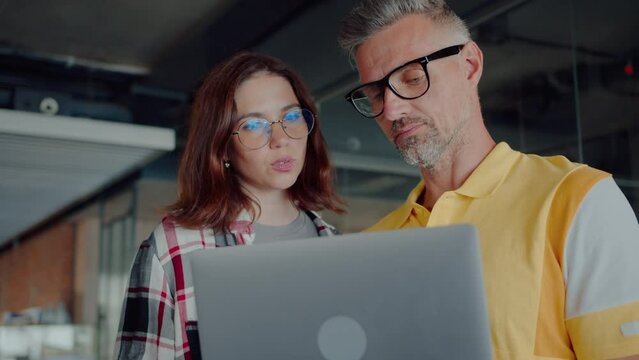 Female trainee standing by programmer and asking for advice