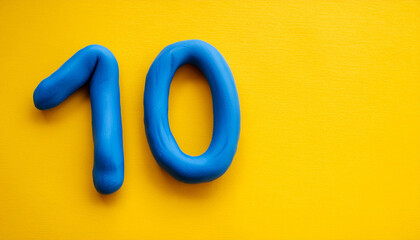 Numbers 10 made of blue plasticine on yellow background. Math learning, development. Flat lay