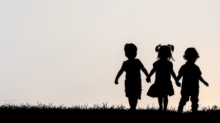Silhouette of three children holding hands, walking on grass against sunset, symbolizing friendship and innocence.