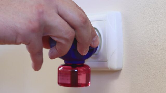 A Man Inserts an Electric Mosquito Fumigator Into a Socket