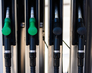 Fuel pump nozzles at a gas station, featuring both green and black handles. The image showcases the...