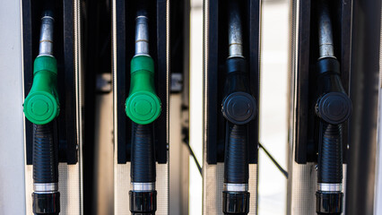Fuel pump nozzles at a gas station, featuring both green and black handles. The image showcases the...