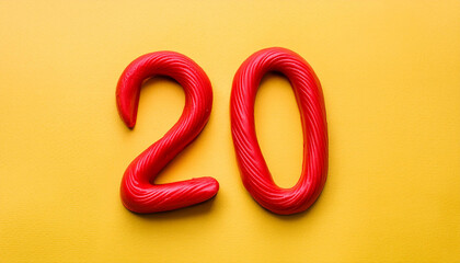 Fototapeta premium Numbers 20 made of red plasticine on yellow background. Math learning, development. Flat lay