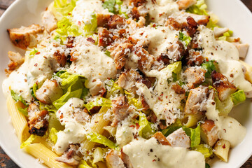 Chicken Caesar Pasta Salad with sauce in white plate. Healthy food.