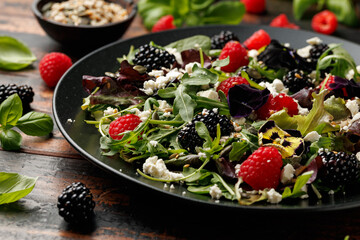 Fototapeta premium Summer berries salad with edible flowers, feta cheese and seeds
