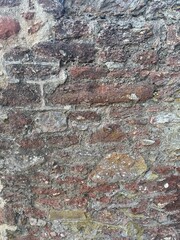 old stone wall with moss and weeds grunge background texture