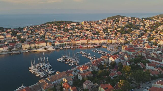 Aerial sunset shot of Mali Losinj old Venetian town in Croatia, Losinj island. Marina with yacht, old houses and church in Mali Losinj. Sea summer travel destination