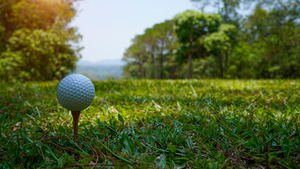 Golf ball on tee in beautiful golf course at sunset background.