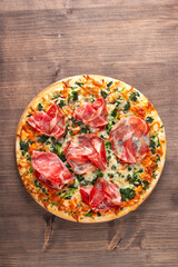 Pizza with prosciutto, ham, arugula, spinach, tomatoes, pesto, cheese and parmesan. Italian cuisine. 