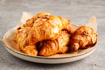 Freshly baked croissants with almonds on a white plate