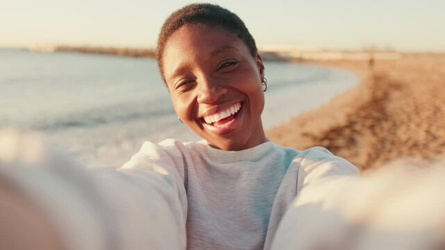 Portrait of a happy girl smiling and taking a selfie while walking by the sea