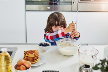 Boy, baking and above in home kitchen, ingredients and mixing bowl or pancake batter in morning apartment. Culinary skills, kid and mixture or cooking breakfast, child development and healthy recipe