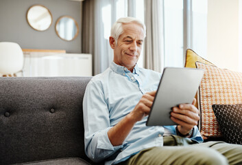 Senior man, tablet and retirement in home for typing email, communication and reading online news. Elderly person, technology and relax on sofa in lounge for bills payment, video and reading ebook