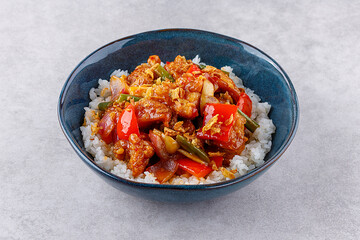 Rice with pork and vegetables in a sweet and sour sauce on a grey background, for a restaurant menu or food delivery