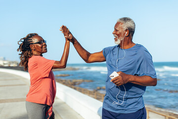 Senior couple high fiving by the seaside celebrating fitness achievements