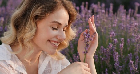 Fototapeta premium Joyful Moment: Young Woman with Lavender Flowers at Dusk