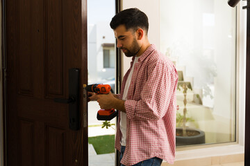 Handyman carefully installing a secure door lock using a screwdriver, ensuring the safety and...
