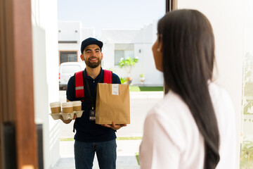 Handsome delivery man delivering takeout food and coffee to a customer at her doorstep