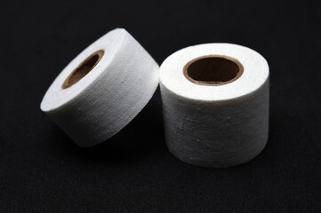 A medical patch on a black background. Two rolls of Band-Aid.