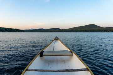 Canoe in a lake surrounded by mountains at sunset. 