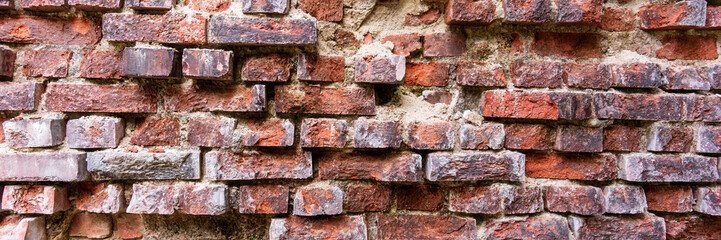 Panoramic image. Uneven old brick wall, bricks have broken out