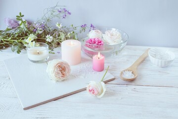 Spa still life with roses and candles on white wooden background